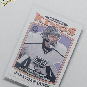 Può includere: Una carta di hockey di Jonathan Quick dei Los Angeles Kings. La carta presenta il logo della squadra e il nome del giocatore. Il testo "SEASON HIGHLIGHTS" e "CHICAGO - 14 marzo 2016" sono visibili.