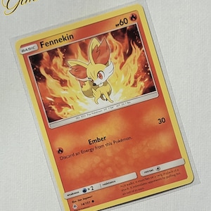 May include: A Fennekin Pokemon card from the XY series. The card is number 14/131 and features a cartoon image of Fennekin with a fire background. The card's name, type, and attack are listed on the card.