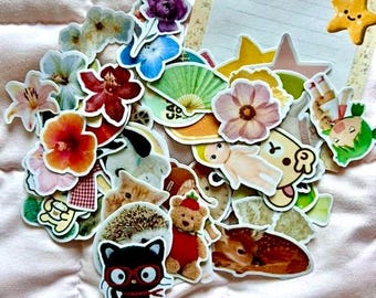 May include: A collection of colorful stickers featuring animals, flowers, and other cute designs. The stickers are arranged on a pink quilted surface.