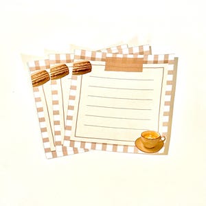 Könnte beinhalten: Ein Satz von vier Notizblättern mit braunem und weißem Karomuster, einem braunen Macaron und einer Tasse Kaffee. Die Notizblätter haben einen linierten Schreibbereich.