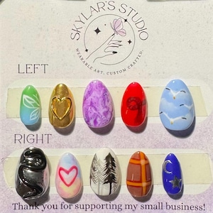 May include: Ten artificial nails with diverse designs and colours. The nails display patterns such as a heart, marble effect, and a forest scene. The colour palette includes green, gold, purple, red, and blue. The text "Skylar's Studio" is visible.