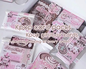 Puede incluir: Una colección de paquetes de tarjetas Kpop y tarjetas de chicas/chicos Kpop con esquemas de color rosa y marrón y la marca Angel Cafe. Los artículos están empaquetados en fundas de plástico transparente y una caja blanca con ilustraciones.