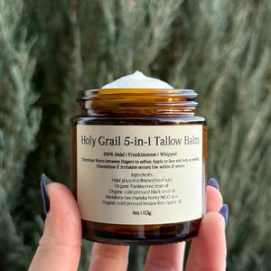 May include: A brown glass jar of "Holy Grail 5-in-1 Tallow Balm" with a white cream on top. The label lists ingredients like Halal beef suet, frankincense resin, and black seed oil. The jar contains 4oz or 113g of product.