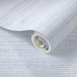 May include: A roll of wallpaper with a textured, woven appearance. The wallpaper features a pattern of vertical and horizontal lines in shades of blue and white, creating a grid-like design. The roll is partially unrolled, revealing the paper's interior.