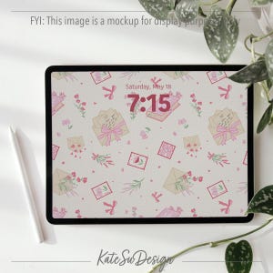 Peut inclure: Une tablette num&eacute;rique affiche un fond d'&eacute;cran orn&eacute; d'illustrations roses et beiges d'enveloppes, de fleurs et de n&oelig;uds. L'heure 7h15 est affich&eacute;e, ainsi que la date, samedi 18 mai. Un stylet blanc est &agrave; gauche.
