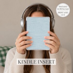May include: A light blue Kindle insert with a white wave pattern. The text "KINDLE INSERT" is displayed at the bottom. A circular sticker in the upper right corner reads "INSTANT DOWNLOAD PRINT AND CUT".