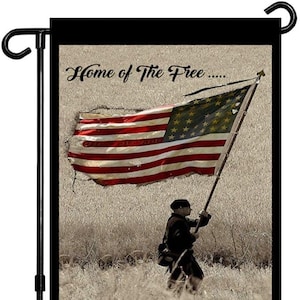 May include: A garden flag with a faded American flag and a soldier holding the flagpole. The text on the flag reads "Home of the Free... Because of the Brave".
