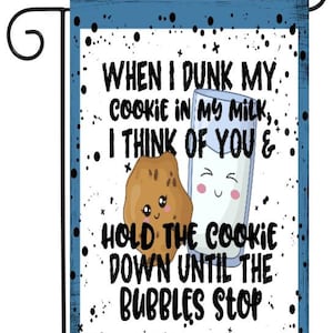 May include: A blue and white garden flag with a cartoon cookie and glass of milk. The text reads "WHEN I DUNK MY COOKIE IN MY MILK, I THINK OF YOU & HOLD THE COOKIE DOWN UNTIL THE BUBBLES STOP".