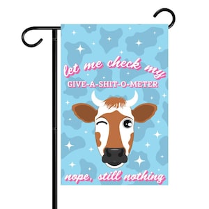 Könnte beinhalten: Eine blaue Gartenflagge mit einer Comic-Kuh und dem Text "let me check my GIVE-A-SHIT-O-METER nope, still nothing".