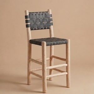 May include: A bar stool featuring a light-colored, natural wood frame with four cylindrical legs and horizontal support rungs. The seat and backrest are constructed from wide, black leather straps woven in a grid pattern across the frame.