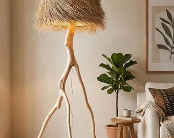 May include: A unique floor lamp with a natural, organic design. The lamp features a light-colored, wooden base with three legs and a textured, woven lampshade. The shade is made of a light brown material, and the lamp is placed on a woven rug.