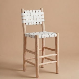 May include: A bar stool featuring a light-toned natural wood frame with four cylindrical legs and horizontal support rungs. The seat and backrest are constructed from wide, white woven straps arranged in a grid pattern for support.