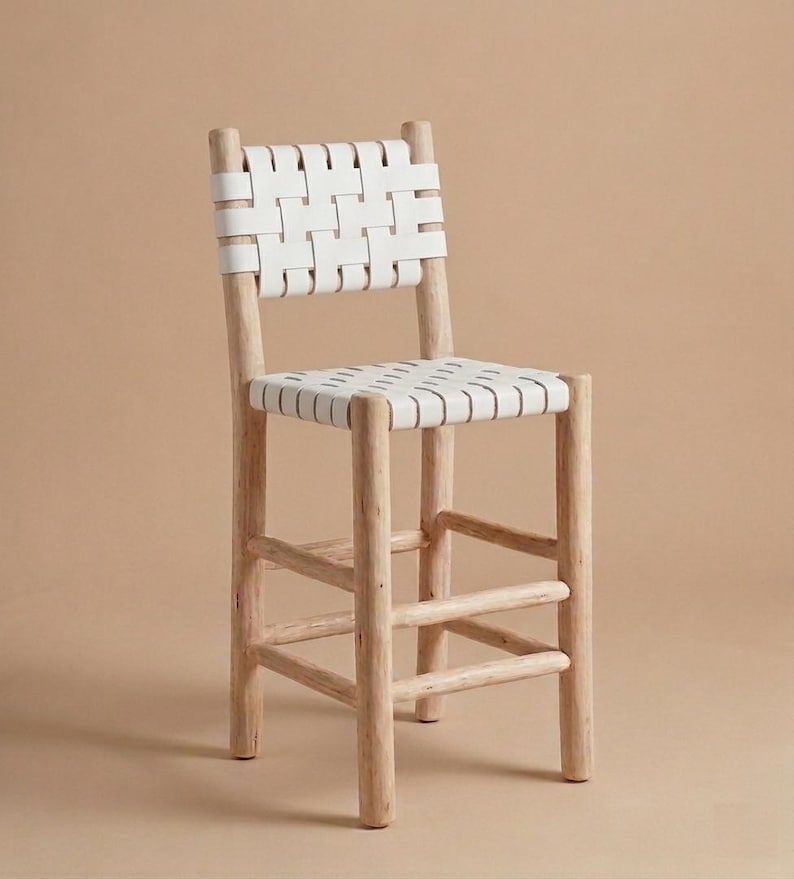 May include: A bar stool featuring a light-toned natural wood frame with four cylindrical legs and horizontal support rungs. The seat and backrest are constructed from wide, white woven straps arranged in a grid pattern for support.