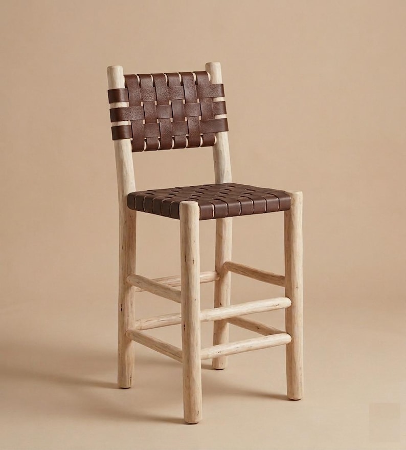 May include: A bar stool featuring a frame constructed from light-colored, natural wood with a visible grain. The seat and backrest are composed of dark brown leather strips woven together in a grid pattern, supported by four legs and horizontal rungs.