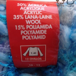 May include: A red label with white text detailing the yarn composition: 50% Acrylic, 35% Wool, 15% Polyamide. The label also includes a white graphic of a sweater with the text "T. 40" and "12 Ovillos" and "10-12". The yarn is a blue and white fuzzy texture.