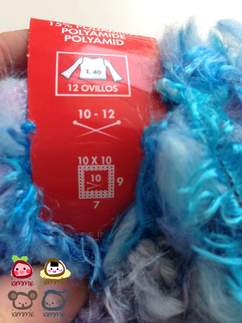 May include: A red label with white text that reads "15% Poliam Polyamide Polyamid" and "T. 40 12 Ovillos 10-12 10 x 10 10 9 7 FIN". The label is attached to a skein of blue and white yarn.