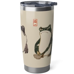 Könnte beinhalten: Eine Edelstahl-Reise-Thermoskanne mit cremefarbenem Hintergrund und einem Design aus drei Fröschen. Die Frösche sind im japanischen Stil mit schwarzer Tinte gezeichnet. Der Text "聞" ist in Rot auf der Thermoskanne.