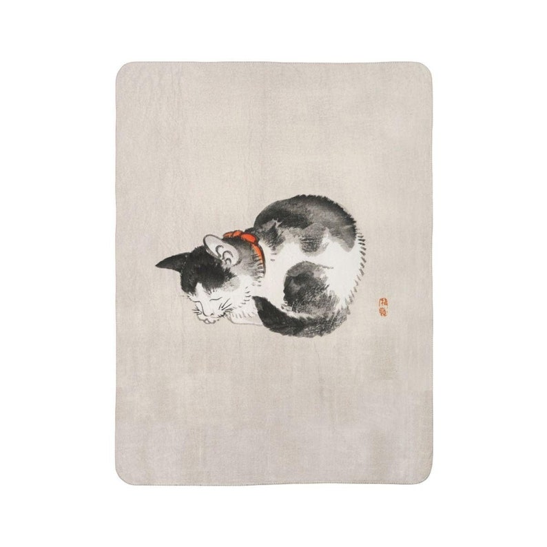 May include: A black and white cat with a red collar is curled up and sleeping on a light beige background. The cat's eyes are closed and its paws are tucked under its body.
