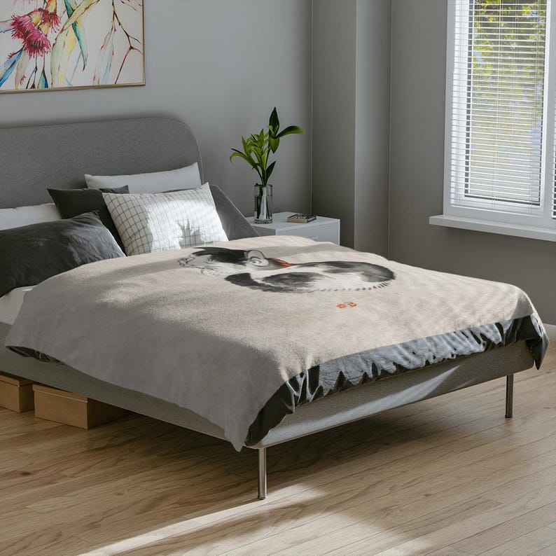 May include: A gray bed with a white and gray patterned duvet cover featuring a black and white ink drawing of a cat. The bed has a gray headboard and a black and gray footboard.