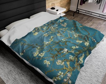 May include: A blue and white throw blanket featuring a painting of a blooming almond tree. The blanket is made of soft, comfortable fabric and is perfect for adding a touch of art to your home decor.