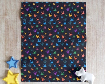 May include: A black sheet of wrapping paper with a repeating pattern of colorful origami cranes. The cranes are in shades of red, orange, yellow, green, blue, and purple.