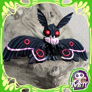 May include: A black moth figurine with red eyes and accents. The moth has large wings with pink and red details. The figurine is set against a gray background and has the "Twisty Prints" logo in the bottom right corner.