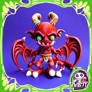 May include: A red figurine of a cartoon devil with green eyes, horns, and wings. The devil has a menacing expression and is posed on a blue background. The figurine has a yellow loincloth and white teeth. The Twisty Prints logo is in the bottom right corner.