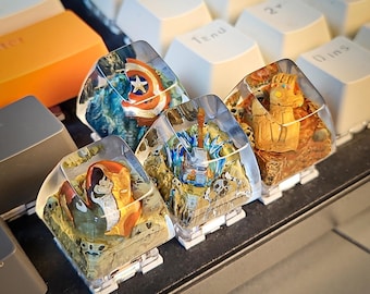 May include: Four clear resin keycaps with different superhero themed designs. The keycaps feature Captain America, Thor, Iron Man, and Thanos. The keycaps are on a keyboard.
