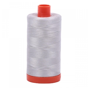 Puede incluir: Un carrete cilíndrico de hilo de coser gris claro enrollado firmemente alrededor de un núcleo central. El carrete presenta una tapa de plástico naranja brillante en la parte superior y una base de plástico naranja a juego, contrastando con el hilo.