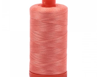 May include: A spool of coral-colored sewing thread wound tightly around a cylindrical core. The spool features a bright orange-red plastic top and base, with the embossed text AURIFIL visible along the bottom edge of the plastic base.