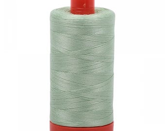 Może przedstawiać: Szpulka jasnozielonej nici do szycia z czerwoną plastikową szpulką.