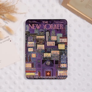 Peut inclure: Une couverture rectangulaire du magazine The New Yorker du 16 décembre 1961, avec une illustration de paysage urbain nocturne dans des tons de violet, de bleu et de jaune. L'illustration de la couverture représente des bâtiments avec des fenêtres éclairées et une église. Le texte "THE NEW YORKER" est bien en évidence.