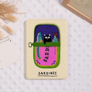 May include: A rectangular phone case with a sardine can design. The green can has a pink label reading "Sardines." Inside, a black cat sits between two colourful fish. The word "Sardines" is printed at the bottom of the case.
