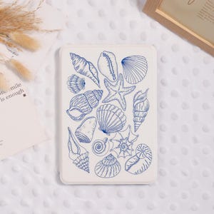 May include: A white rectangular case featuring a blue line drawing of various seashells and a starfish. The design includes different types of shells, such as conch shells, scallops, and spiral shells. The case is likely for a tablet or e-reader.