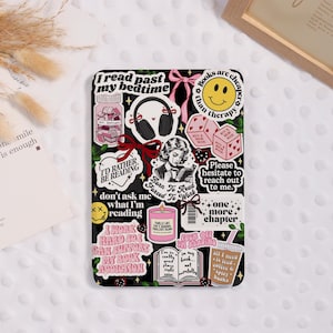 May include: Black phone case covered in stickers with a reading theme. Stickers include phrases like "I'd rather be reading," "Books are cheaper than therapy," and "Born to read, forced to work." Other stickers feature books, headphones, and a smiley face.
