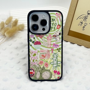 May include: A green, white and pink phone case with a variety of colourful stickers and illustrations. The case features a cat, a bird, a dog, a clock and a strawberry. The text "N to T!" is visible on the case.