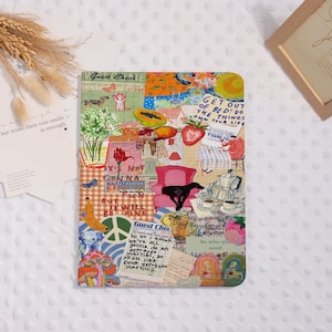May include: A colorful collage-style notebook cover with various illustrations and text. The design includes images of a dog, fruit, flowers, and text that reads "Get out of bed! Do the things own your life." The notebook is a unique and artistic item.
