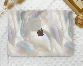 May include: A white laptop computer with a pearlescent shell design. The laptop has a silver Apple logo on the lid.