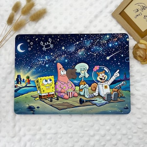 May include: A rectangular laptop skin featuring a starry night sky with SpongeBob SquarePants, Patrick Star, Squidward Tentacles, and Sandy Cheeks sitting on a blanket. The characters are stargazing near a telescope and a pineapple house.