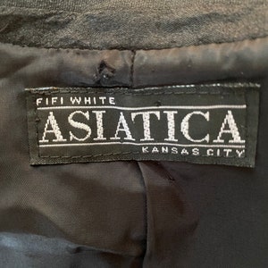 Puede incluir: Una etiqueta negra con texto blanco que dice "Fifi White Asiatica Kansas City".