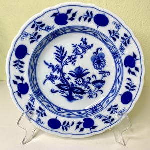 May include: A blue and white porcelain plate with a floral design. The plate has a scalloped edge and is decorated with a blue floral pattern on a white background.