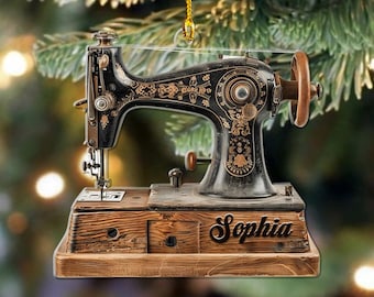 May include: A vintage-style sewing machine ornament with intricate gold detailing on a black body. The wooden base is engraved with the name "Sophia". The ornament hangs from a gold string, perfect for holiday decor.