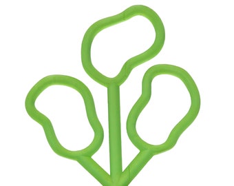 May include: A green plastic toy with three loops, resembling a stylized flower.