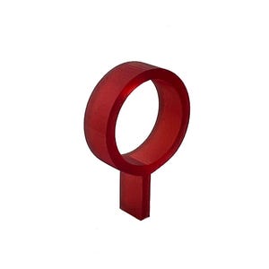 Puede incluir: Un anillo rojo translúcido con una base rectangular. El anillo es de forma continua y la base es una extensión rectangular corta. El objeto está sobre un fondo blanco.