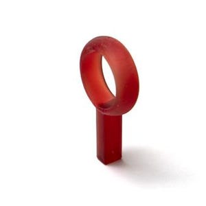 May include: A translucent red ring with a rectangular base. The ring is a solid band with a smooth, matte finish. The object is set against a white background, casting a soft shadow.