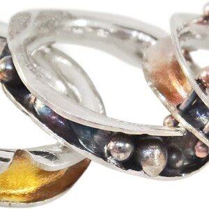 May include: Five silver rings with different coloured accents. The rings are stacked on top of each other. The accents include gold, copper, and black.