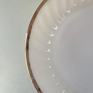 May include: A white ceramic plate with a gold rim. The plate has a rippled design.