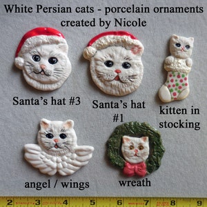 May include: Porcelain ornaments featuring white Persian cats. Designs include a cat in a Santa hat, a cat with angel wings, a cat in a wreath, and a kitten in a stocking. The text says "White Persian cats - porcelain ornaments created by Nicole."