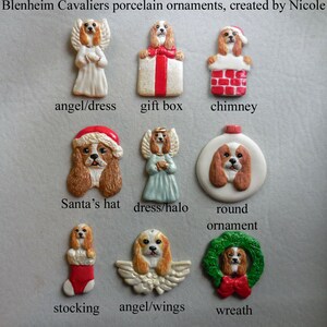May include: A collection of Blenheim Cavalier porcelain ornaments. The ornaments feature Cavalier King Charles Spaniels in various designs, including an angel, gift box, chimney, Santa's hat, dress/halo, round ornament, stocking, angel/wings, and wreath.
