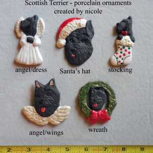 May include: A collection of Scottish Terrier porcelain ornaments. The ornaments include a terrier in a Santa hat, angel wings, a dress, a wreath, and a stocking. The text "Scottish Terrier - porcelain ornaments created by nicole" is visible.